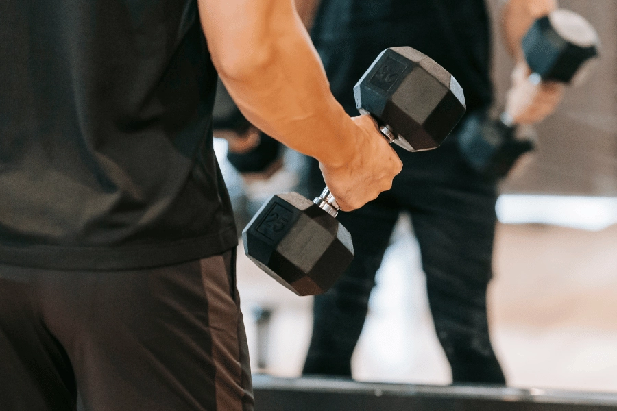 man lifting free weights at the gym in front of a mirror